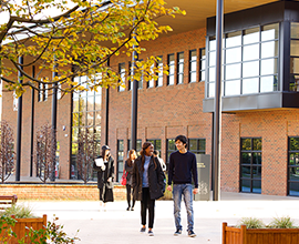 A couple of students walking outside the health sciences building on an autumn day